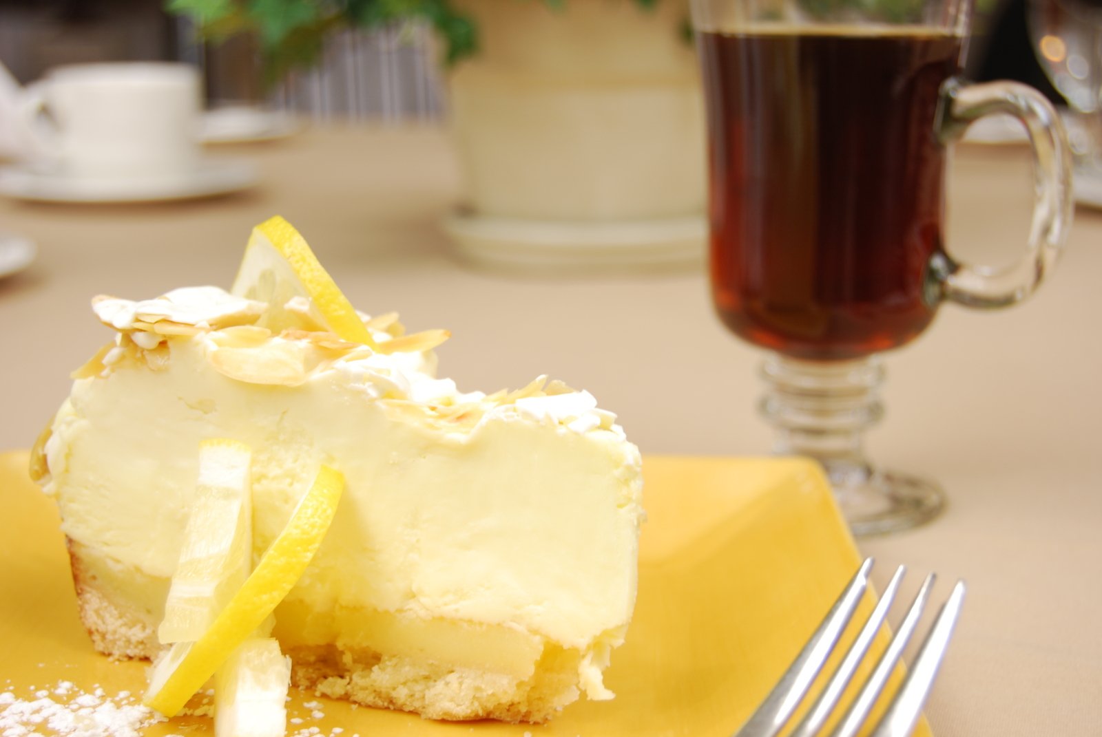 a desert cake on a plate sitting on a table with a fork and glass of tea