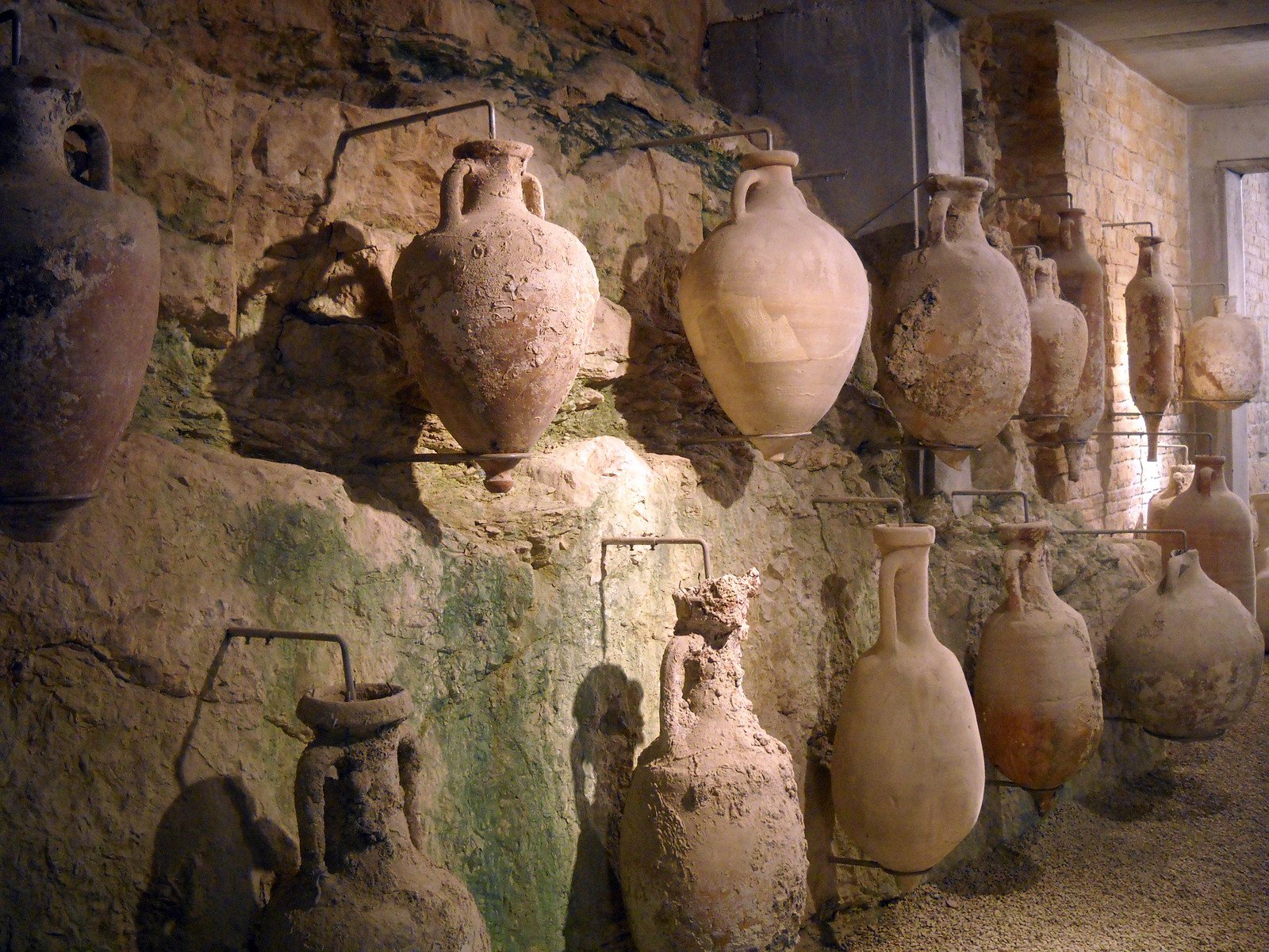 a bunch of ceramic pots lined up on the side of a stone wall