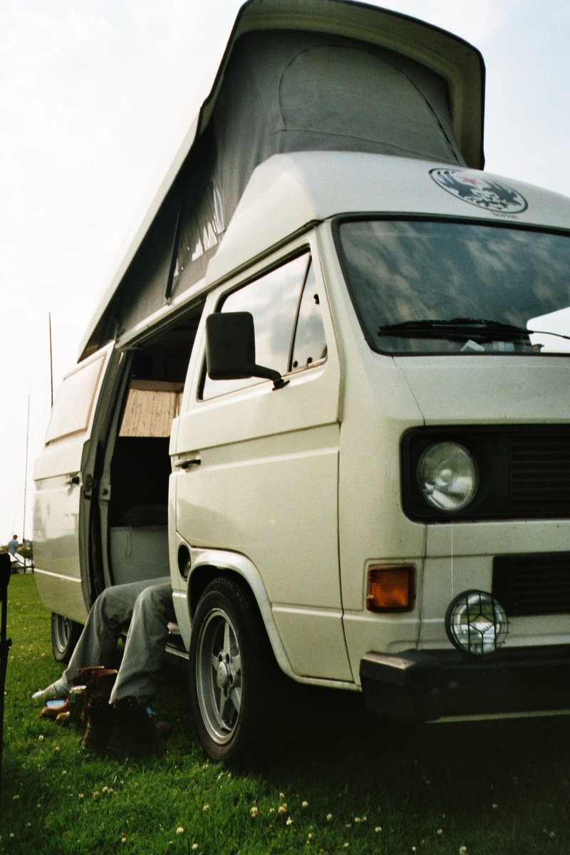 a man is lying in front of a van that is parked on grass