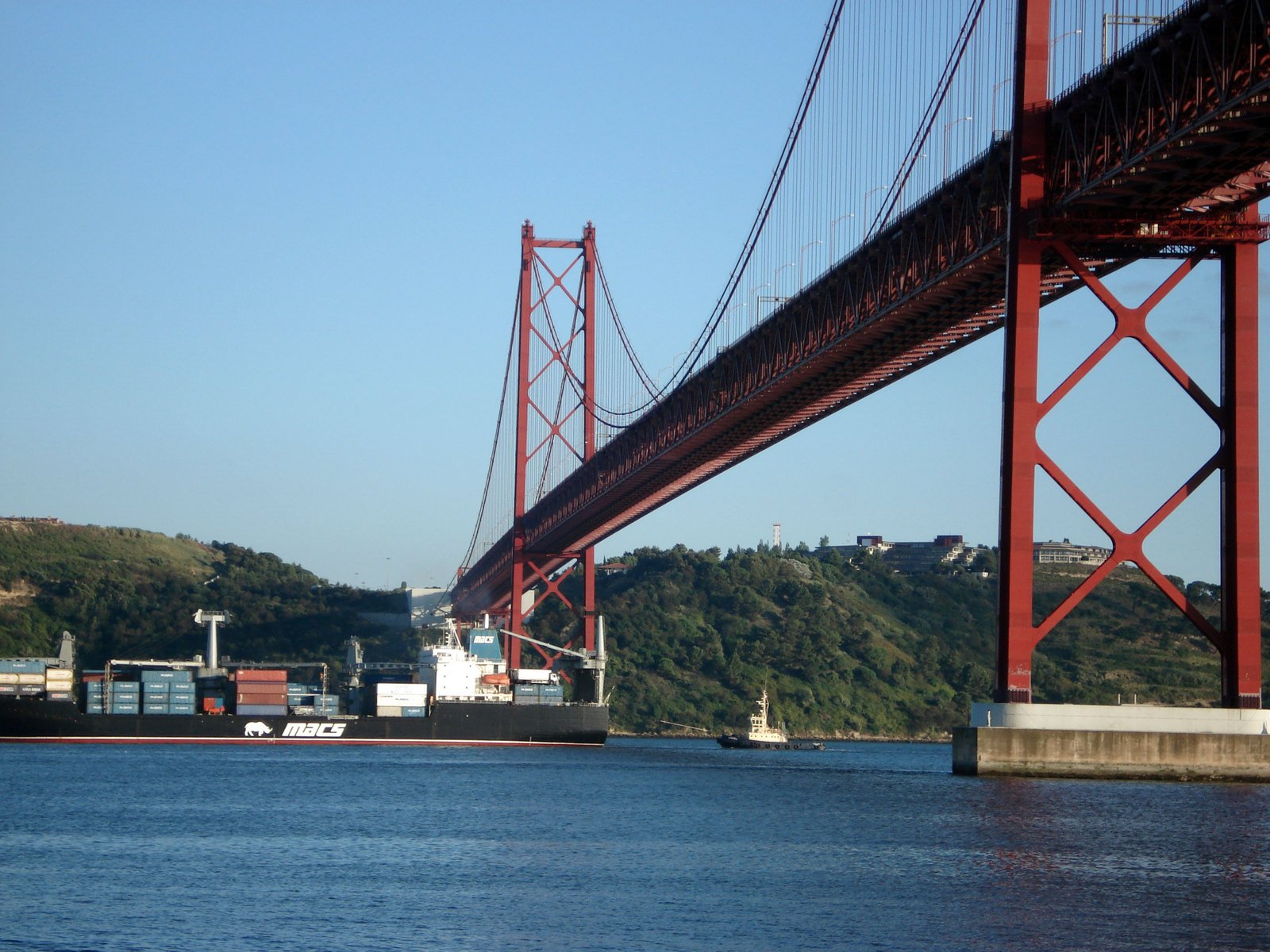 a large cargo ship is passing underneath a bridge