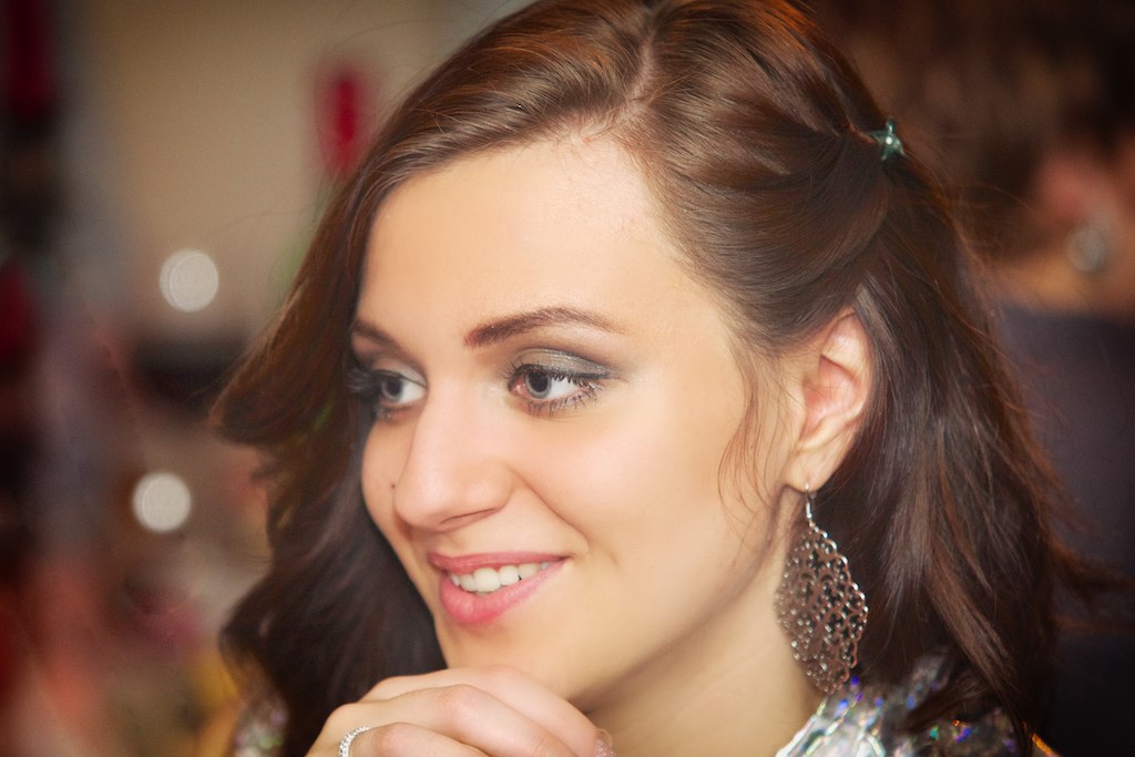 a smiling woman wearing a jewelled necklace and earrings