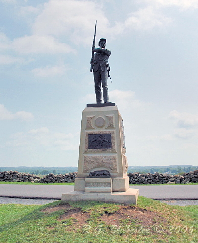 a statue with a sword stands on a pedestal in the grass