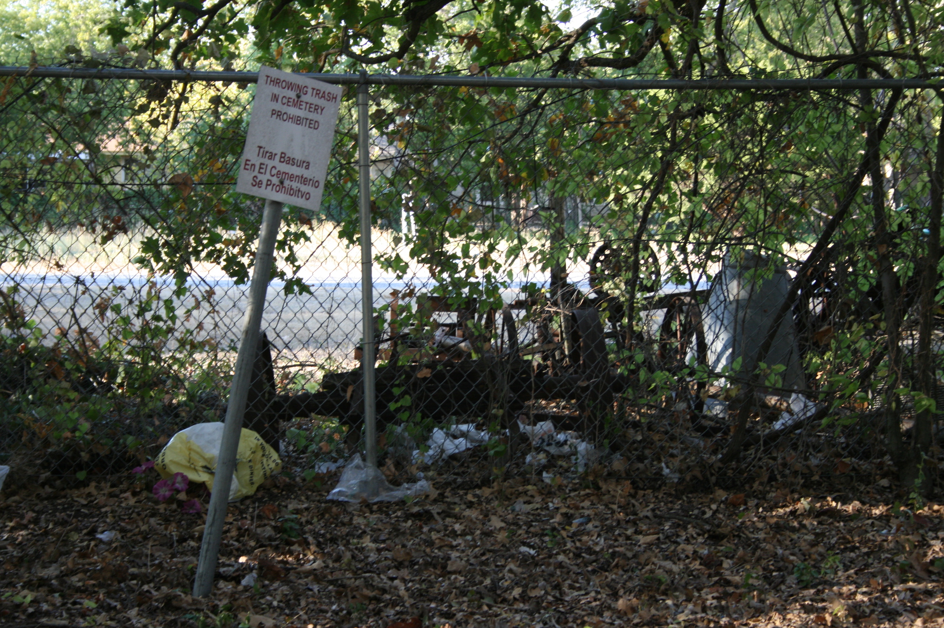 a sign behind a fence near an overgrown gate