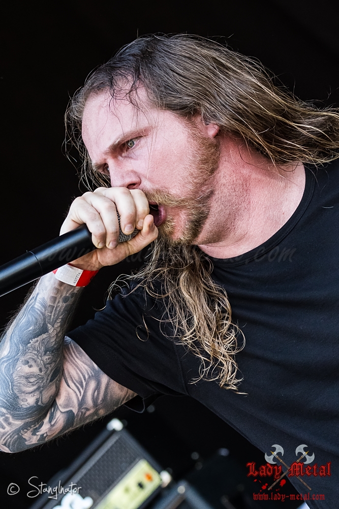 a man with long hair and tattoos holding a microphone