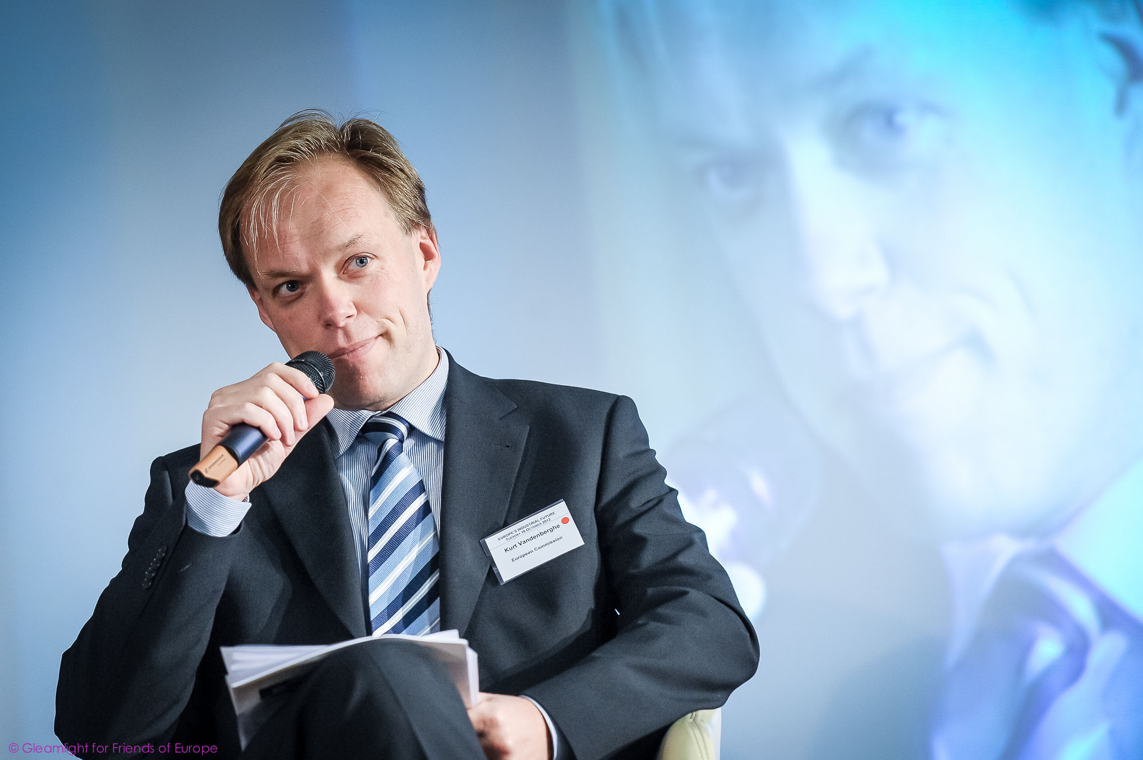 a man sitting in a chair talking into a microphone