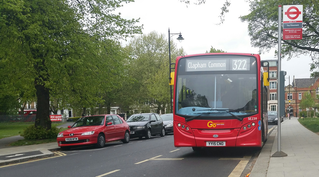 the large red bus is on the side of the street