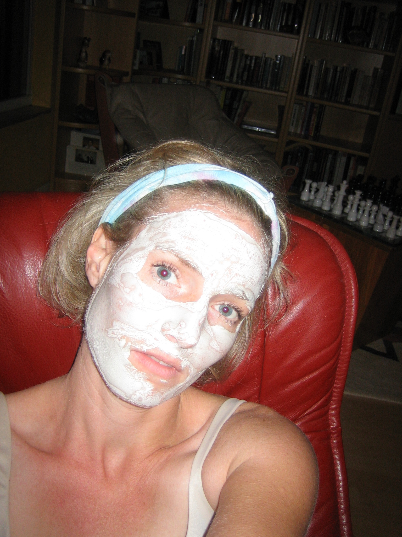 a girl is using a white clay mask