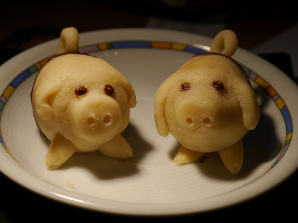 two miniature pigs on a plate, each facing the same direction