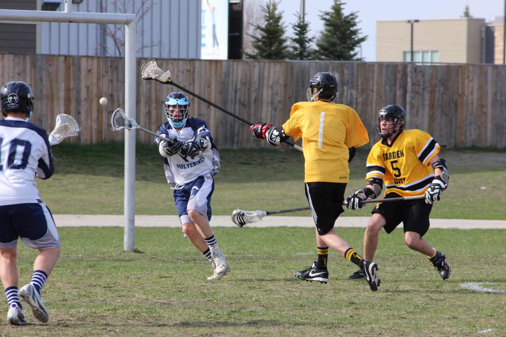 three people in yellow jerseys are playing lacrosse