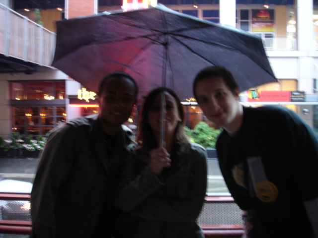 three people holding a large umbrella in the rain
