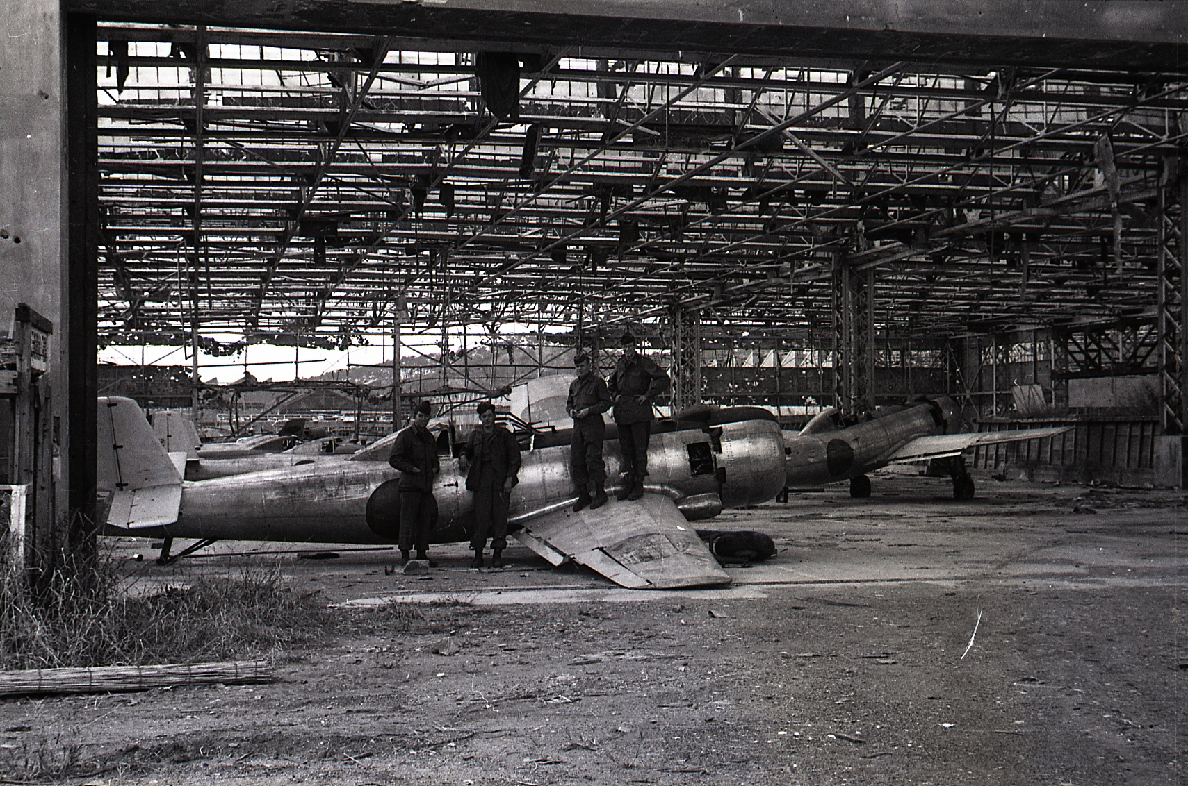 two men stand in front of an airplane under a building