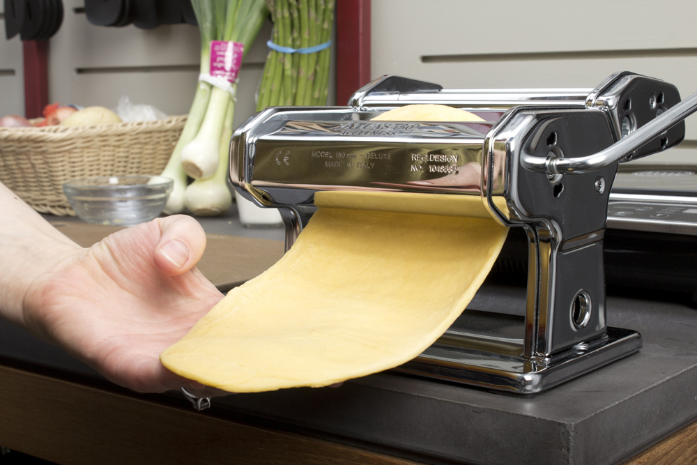 person holding a pasta roller making soing yellow