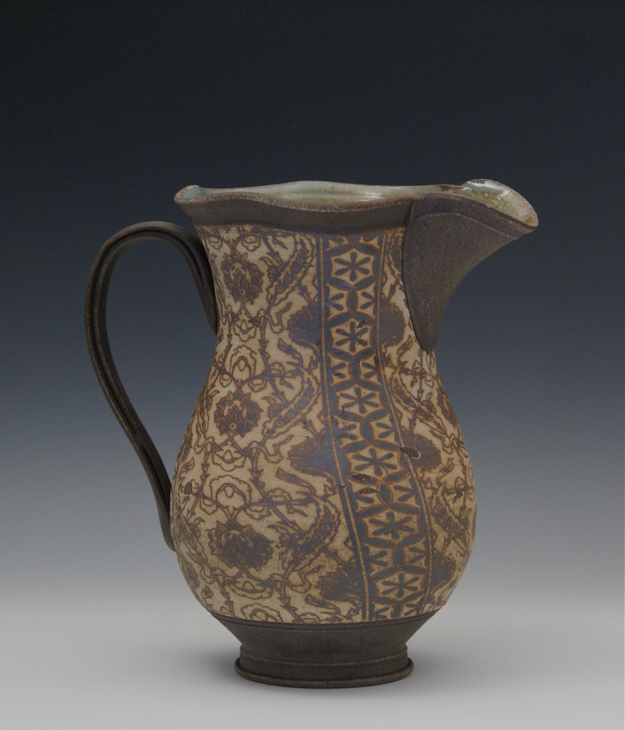 an ancient ceramic pitcher with ornate designs on it
