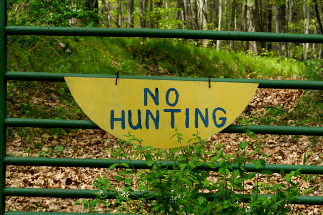a sign with a wooden base on the fence