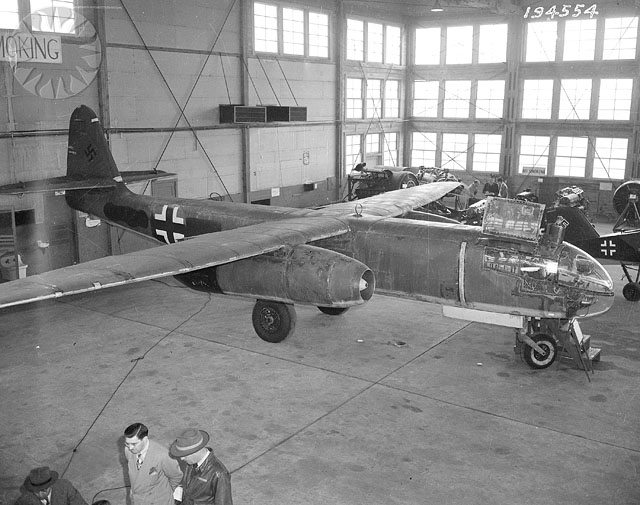 people look at a war plane in a garage