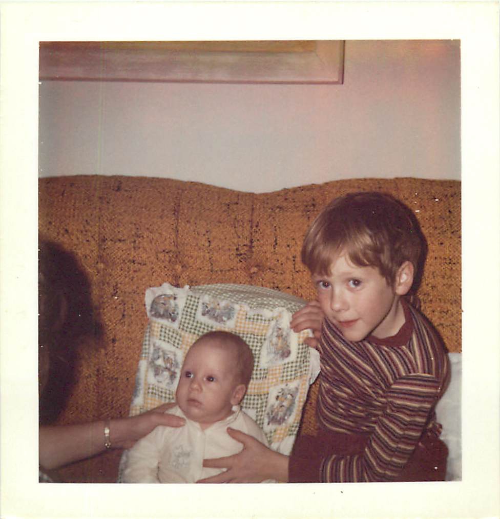 the  is holding his mom's hand as they are sitting on a couch