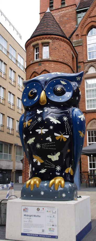 the large blue owl is sitting outside of a building