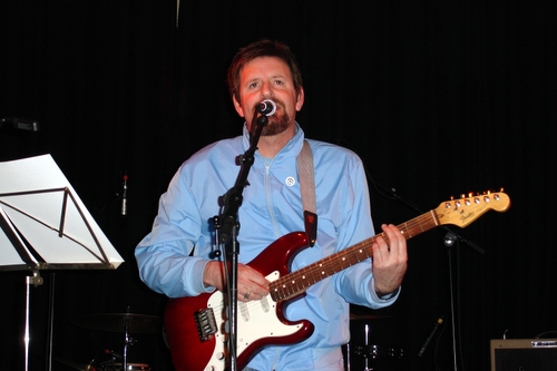 a man in blue shirt playing guitar with microphone