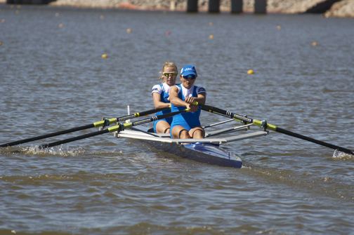 two women in blue outfits rowing in a boat