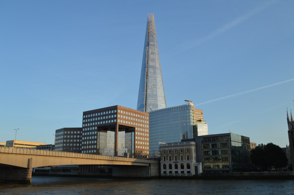 two towers rise above some buildings near a body of water