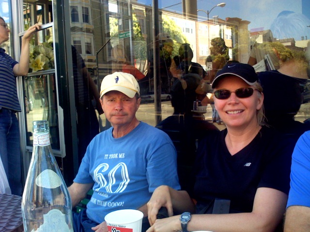 several people are sitting at an outdoor table having coffee and wine