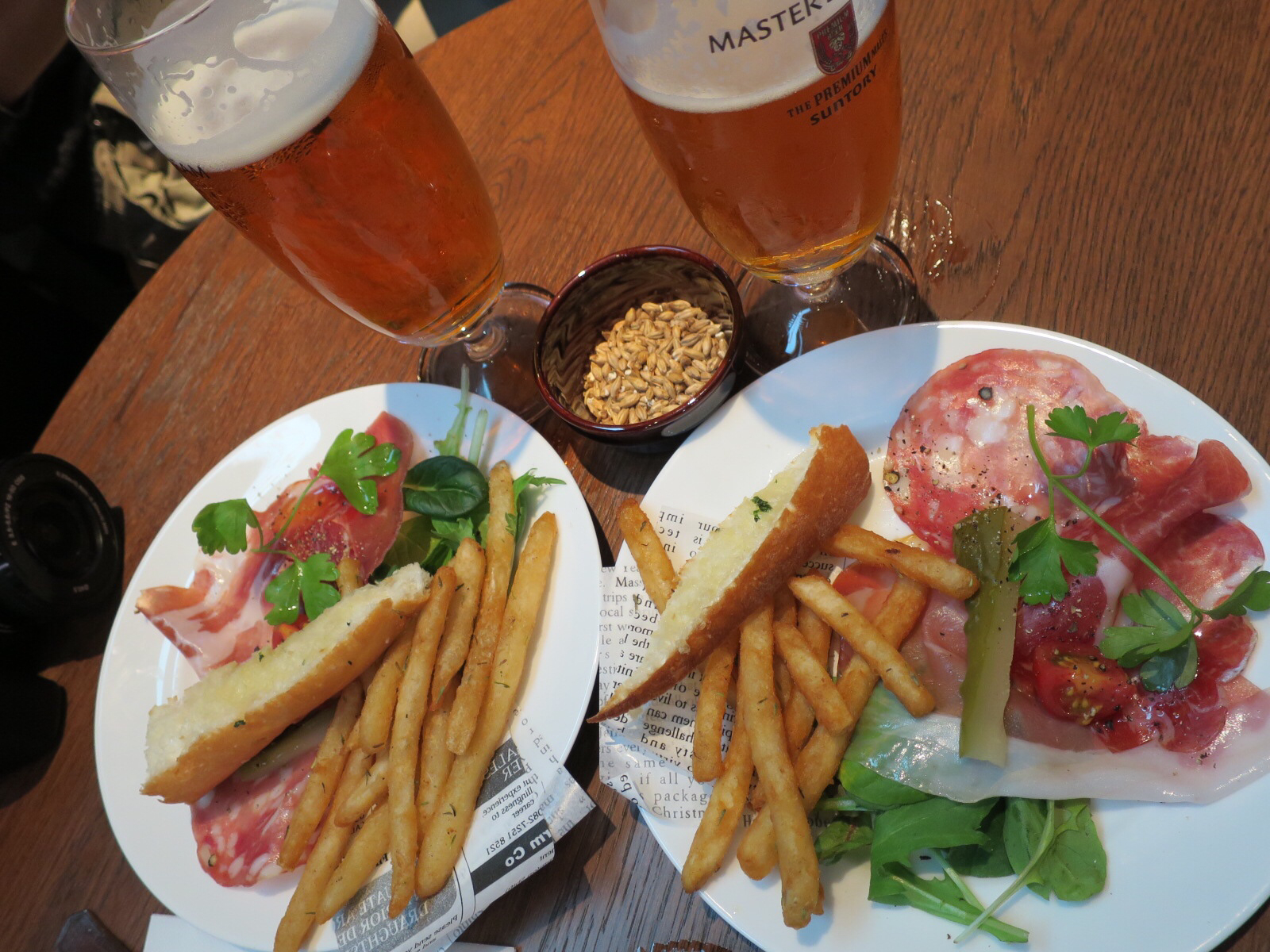 two plates with french fries, ham and a glass of beer