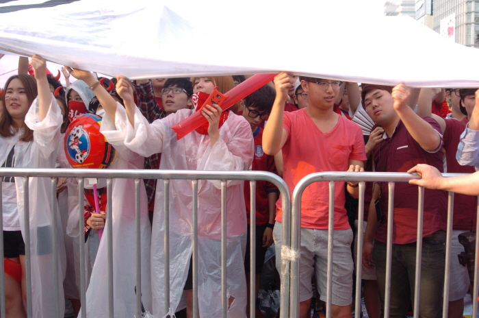 a group of people standing next to a white fence