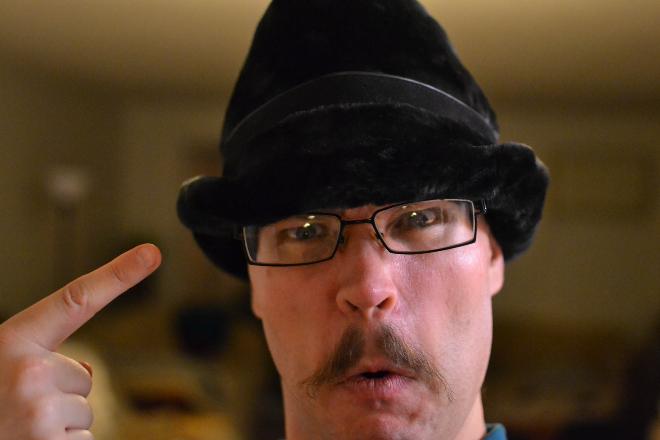 a man wearing a hat and glasses is pointing up