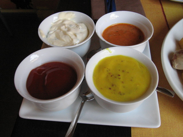 three different bowls of soup on a plate with spoons