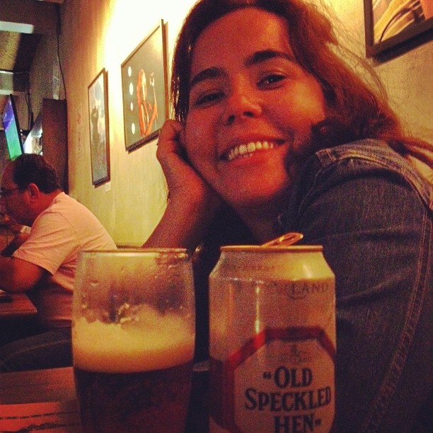 a woman smiling while looking at some drinks in a pub