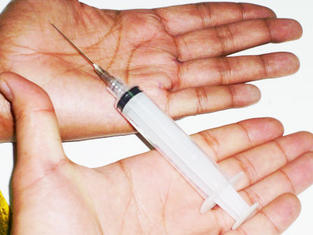 a hand with a needle inside a medical syil