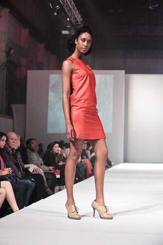 the female in the orange dress is walking down the runway