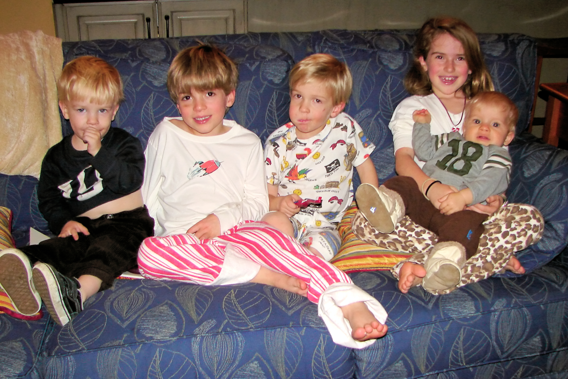 five s are sitting on the sofa while one of them is wearing a pajama top