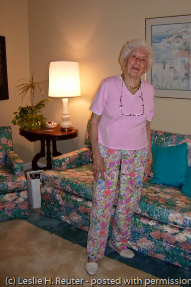 the elderly woman is posing in front of a couch