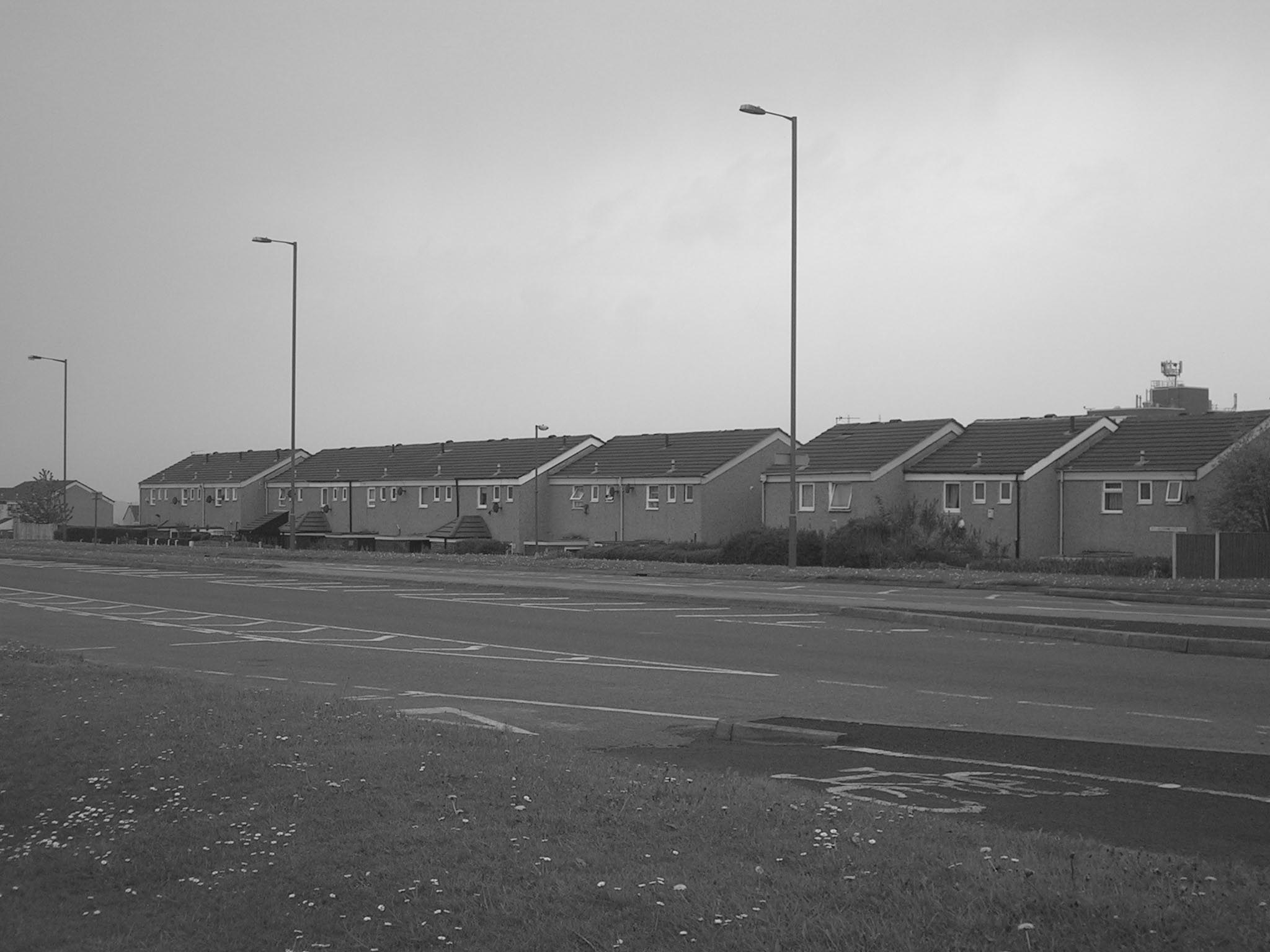 houses on the other side of a road in front of a field