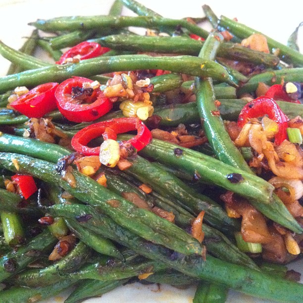 a plate topped with green beans and red peppers