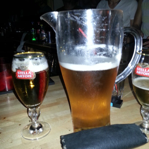 a pitcher of beer is next to three glasses of beer