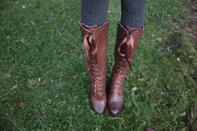 a woman in brown boots is standing on the grass