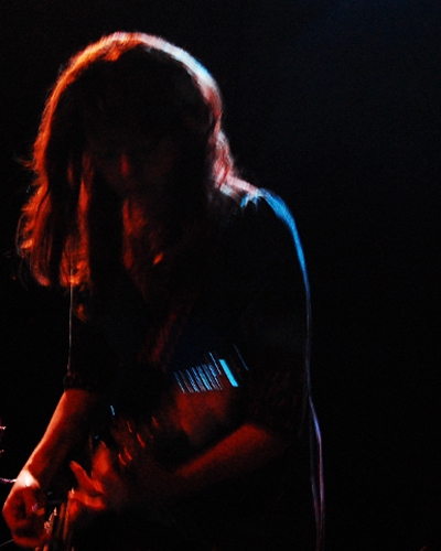 a man holding a guitar while standing in a dark area