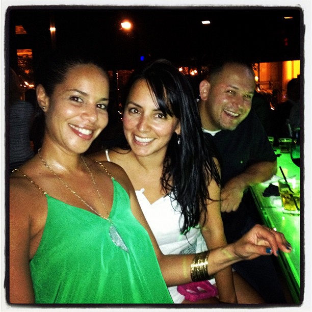 three smiling friends at a bar with bright lights