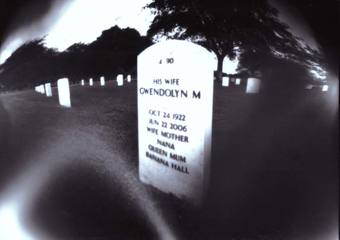 a grave sits near a row of trees and a black - and - white po