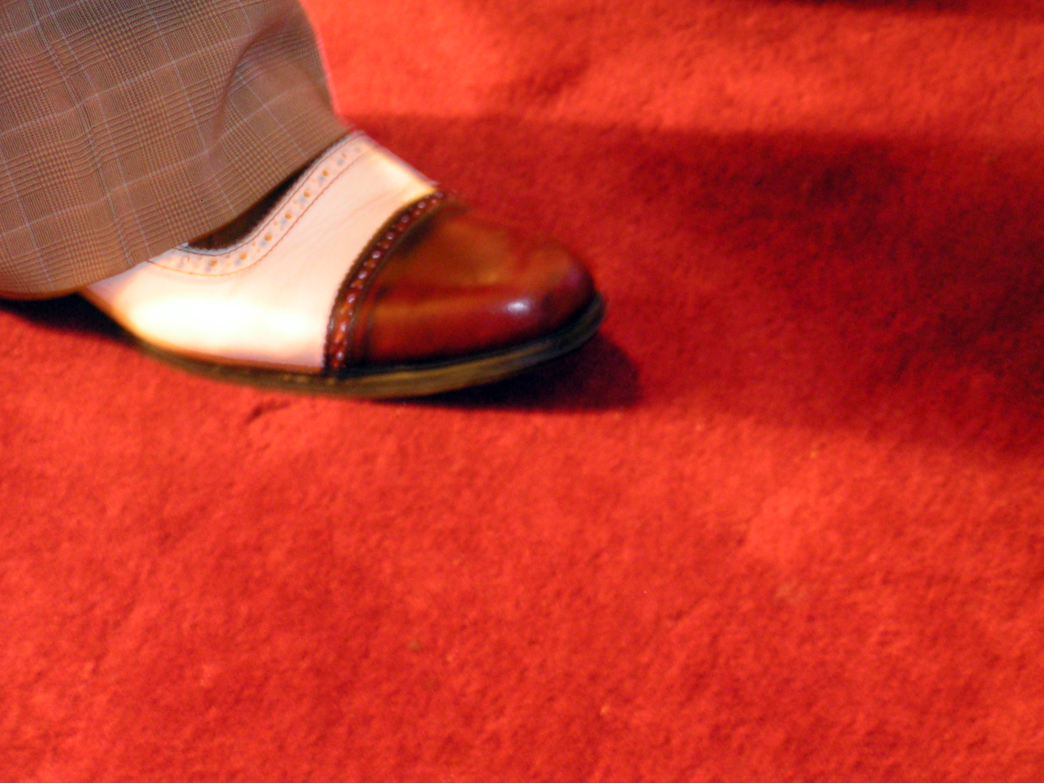 a man with brown shoes and a red carpet