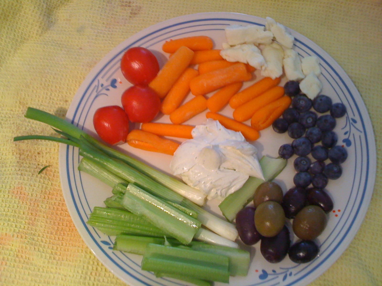 some carrots, celery, olives, and tomatoes on a plate