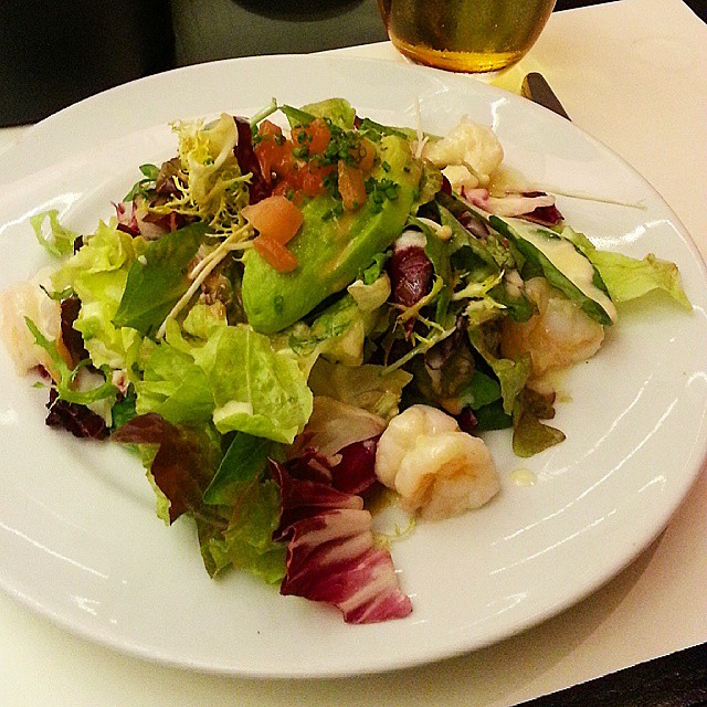 salad with shrimp and lettuce on white plate next to beer