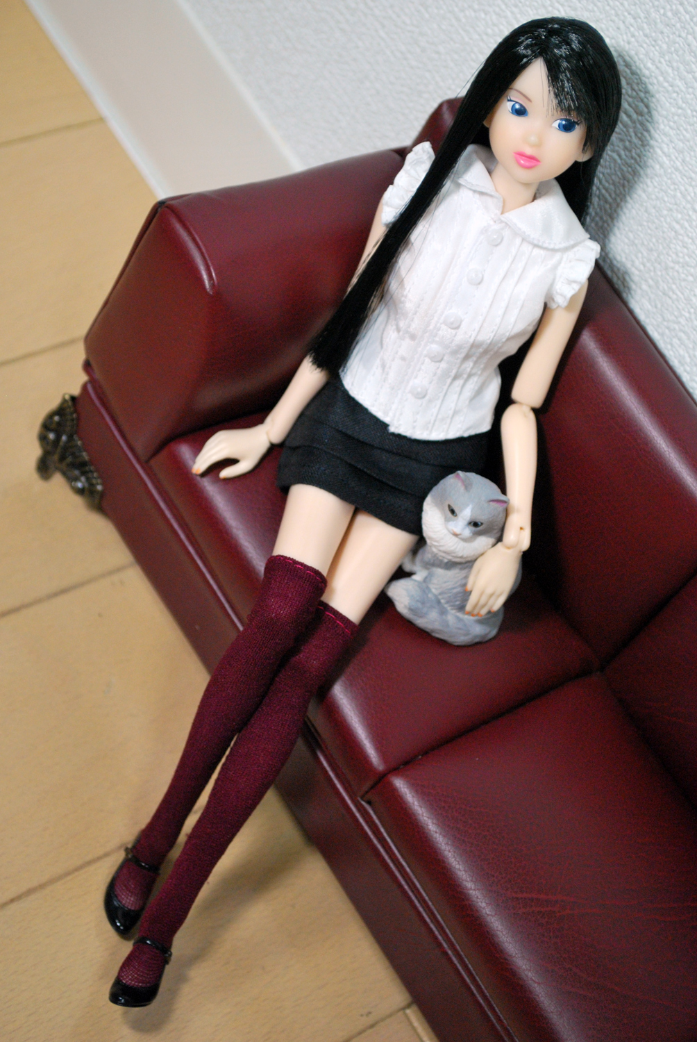 a toy doll wearing black with dark hair and a long black ponytail
