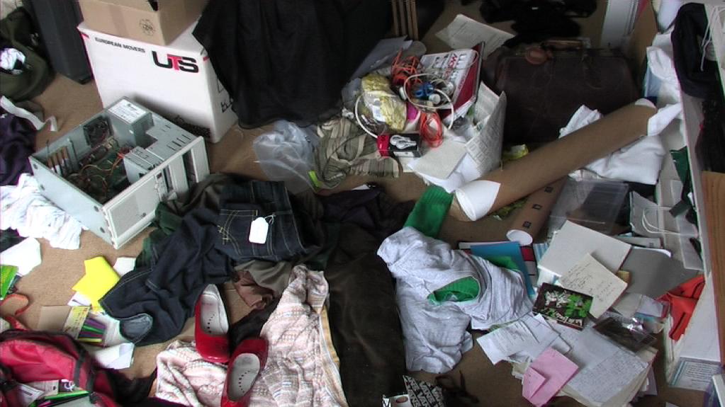 a cluttered floor with a cardboard box and various clothes