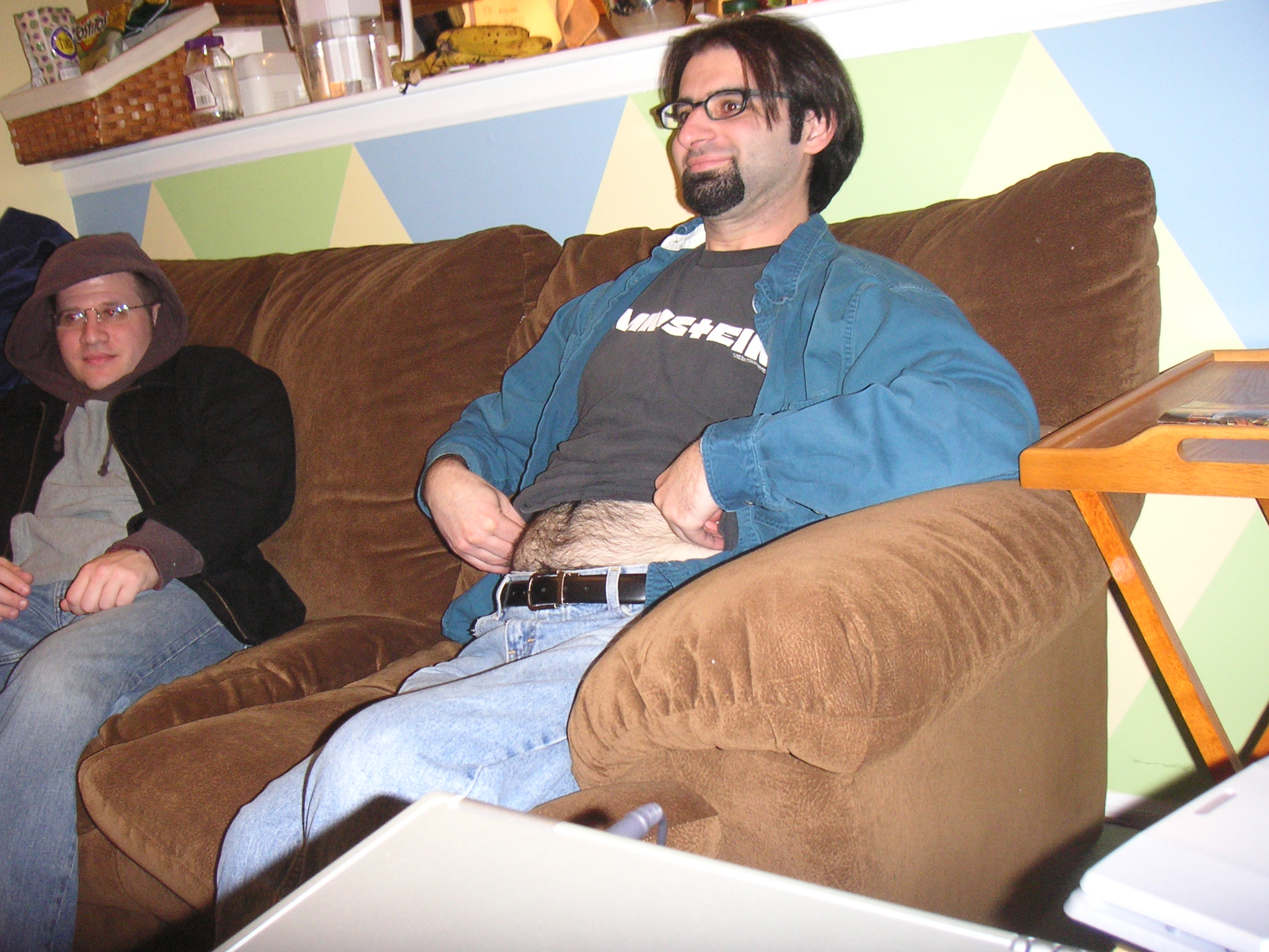 two people sitting on a brown couch with blue and yellow wall behind them