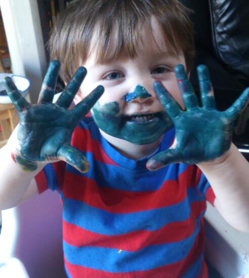 a small boy is making a funny face covered with paint