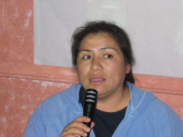 a woman in a blue hoodie holds a microphone and looks ahead