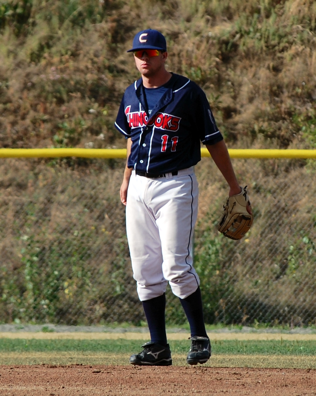 a baseball player stands with his glove on the mound